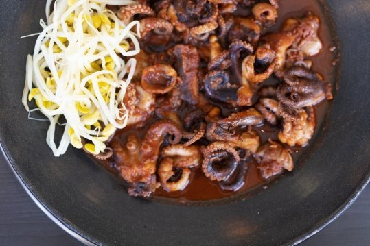 검은 팬 위 쭈꾸미볶음과 콩나물